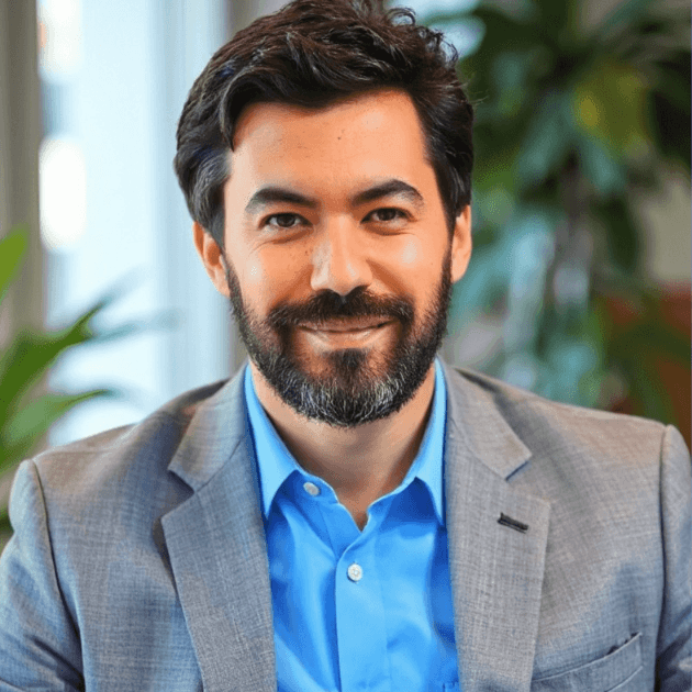 Professional headshot of a man in glasses, blue shirt, and suit, AI headshot photo example